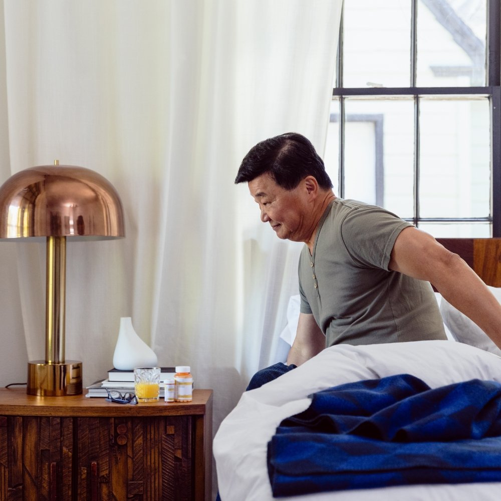 Dizziness after waking up Person sitting on the edge of the bed feeling dizzy after waking up in the morning